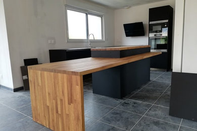 This is an example of a medium sized modern l-shaped kitchen in Lille with an integrated sink, recessed-panel cabinets, wood worktops, integrated appliances and an island.