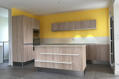 This is an example of a medium sized contemporary l-shaped kitchen/diner in Grenoble with a single-bowl sink, flat-panel cabinets, light wood cabinets, beige splashback, ceramic splashback, stainless steel appliances, ceramic flooring and an island.