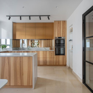 Inspiration pour une cuisine design en U avec un évier encastré, un placard à porte plane, des portes de placard en bois brun, un électroménager en acier inoxydable, une péninsule, un sol beige et un plan de travail blanc.