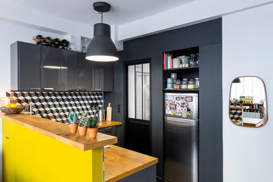 Inspiration for a small contemporary u-shaped kitchen/diner in Paris with a single-bowl sink, flat-panel cabinets, grey cabinets, wood worktops, cement tile splashback, cement flooring, black floors, multi-coloured splashback, stainless steel appliances, a breakfast bar and beige worktops.
