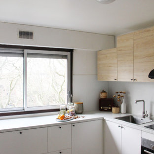 Design ideas for a mid-sized contemporary l-shaped separate kitchen in Toulouse with an integrated sink, flat-panel cabinets, white cabinets, laminate benchtops, white splashback, black appliances, ceramic floors, no island, brown floor and white benchtop.