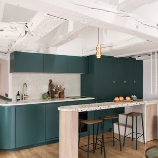 Inspiration for a contemporary galley kitchen in Paris with an undermount sink, flat-panel cabinets, green cabinets, beige splashback, panelled appliances, medium hardwood floors, a peninsula, brown floor and beige benchtop.