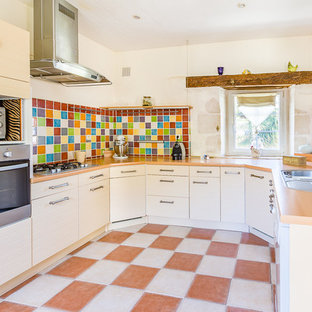 Idées déco pour une cuisine campagne en U avec un évier posé, un placard à porte plane, des portes de placard blanches, un plan de travail en bois, une crédence multicolore, un électroménager en acier inoxydable, un sol multicolore et un plan de travail beige.