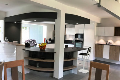Cette image montre une grande cuisine ouverte minimaliste avec des portes de placard blanches, un électroménager en acier inoxydable et îlot.