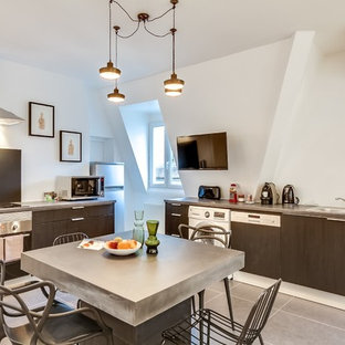 Cette photo montre une grand cuisine américaine tendance en L avec un évier 1 bac, des portes de placard noires, une crédence noire, un électroménager encastrable, un sol en carrelage de céramique et un îlot central.