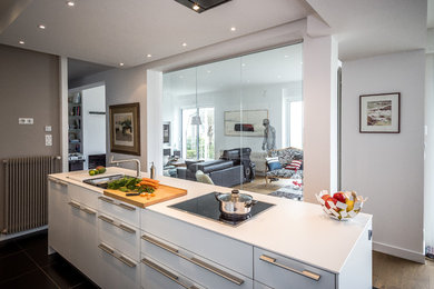 Diseño de cocina comedor actual con fregadero integrado, puertas de armario blancas, encimera de laminado, una isla, encimeras blancas y suelo negro