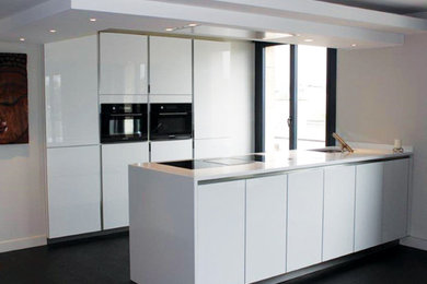 Design ideas for a medium sized contemporary galley open plan kitchen in Lyon with a submerged sink, beaded cabinets, white cabinets, quartz worktops, white splashback, integrated appliances, concrete flooring, an island, black floors and white worktops.