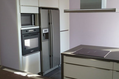 Exemple d'une cuisine ouverte linéaire et encastrable tendance de taille moyenne avec des portes de placard beiges, îlot, un sol gris et un plan de travail marron.