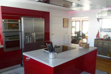 Cette photo montre une cuisine américaine linéaire tendance de taille moyenne avec des portes de placard rouges, un électroménager en acier inoxydable, îlot, un sol gris et un plan de travail gris.
