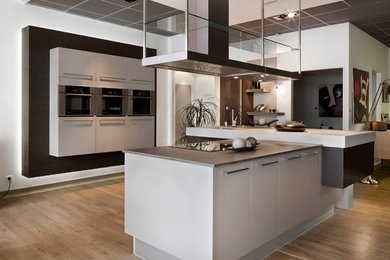 ルアーブルにある高級な広いコンテンポラリースタイルのおしゃれなキッチン (一体型シンク、白いキャビネット、ラミネートカウンター、パネルと同色の調理設備、淡色無垢フローリング) の写真