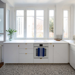 Mittelgroße Moderne Wohnküche ohne Insel in L-Form mit Unterbauwaschbecken, Kassettenfronten, weißen Schränken, Laminat-Arbeitsplatte, Küchenrückwand in Grau, Rückwand aus Marmor, weißen Elektrogeräten, Terrazzo-Boden, grauem Boden und weißer Arbeitsplatte in Paris
