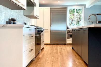 Mid-sized minimalist l-shaped medium tone wood floor and beige floor open concept kitchen photo in San Francisco with an integrated sink, shaker cabinets, white cabinets, marble countertops, metallic backsplash, an island and white countertops