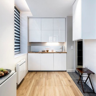 Exemple d'une petit cuisine ouverte linéaire tendance avec un évier posé, des portes de placard blanches, un plan de travail en bois, une crédence métallisée, une crédence en dalle métallique, un sol en bois clair et aucun îlot.