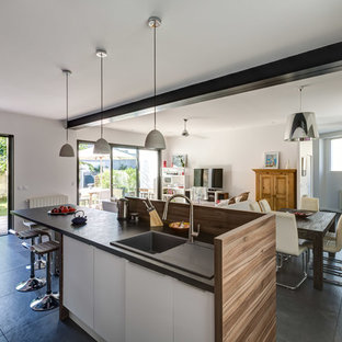 Aménagement d'une cuisine ouverte parallèle contemporaine de taille moyenne avec des portes de placard blanches, un sol en carrelage de céramique et un îlot central.
