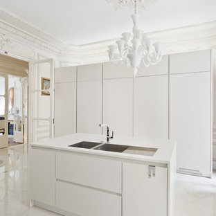 Cette photo montre une cuisine tendance fermée et de taille moyenne avec un évier 2 bacs, un placard à porte plane, des portes de placard blanches, un sol en marbre et un îlot central.