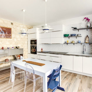 Cette photo montre une grand cuisine ouverte linéaire éclectique avec un évier 2 bacs, des portes de placard blanches, un plan de travail en stratifié, une crédence blanche, une crédence en carreau de céramique, un électroménager noir, un placard à porte plane, aucun îlot, un sol marron et un sol en bois clair.