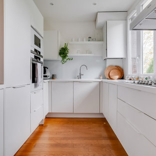 Idées déco pour une petit cuisine ouverte contemporaine en U avec des portes de placard blanches, un plan de travail en quartz, une crédence blanche, une crédence en carreau de verre, un électroménager blanc, un sol en bambou, un sol marron, un plan de travail blanc, un évier posé, un placard à porte plane et aucun îlot.