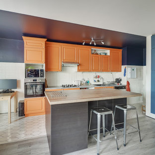 Idée de décoration pour une cuisine linéaire bohème avec un évier 2 bacs, un placard avec porte à panneau surélevé, des portes de placard oranges, une crédence blanche, un îlot central et un plan de travail gris.