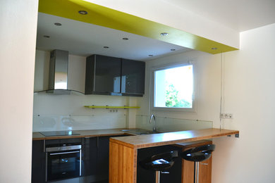 Medium sized contemporary u-shaped kitchen/diner in Grenoble with a submerged sink, grey cabinets, wood worktops, glass tiled splashback, stainless steel appliances, ceramic flooring and grey floors.