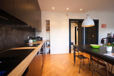 Cette image montre une cuisine américaine linéaire design avec des portes de placard noires et un plan de travail en stratifié.