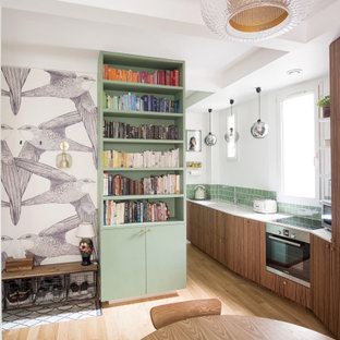 Inspiration pour une cuisine parallèle design avec un évier encastré, un placard à porte plane, des portes de placard en bois brun, une crédence verte, un électroménager en acier inoxydable, un sol en bois clair, aucun îlot, un sol beige et un plan de travail blanc.