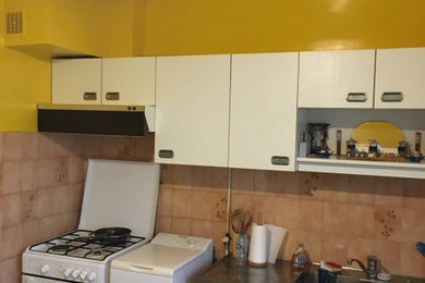 Cette photo montre une cuisine linéaire moderne fermée et de taille moyenne avec un évier 1 bac, des portes de placard blanches, un plan de travail en stratifié, îlot et un sol multicolore.