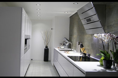 パリにある高級な中くらいなコンテンポラリースタイルのおしゃれなキッチン (シングルシンク、インセット扉のキャビネット、白いキャビネット、ラミネートカウンター、グレーのキッチンパネル、パネルと同色の調理設備、セラミックタイルの床、アイランドなし、グレーの床、白いキッチンカウンター) の写真