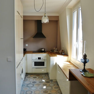 Cette image montre une petit cuisine ouverte traditionnelle en U avec un placard à porte plane, des portes de placard blanches, un plan de travail en bois, une crédence marron, un électroménager blanc et aucun îlot.