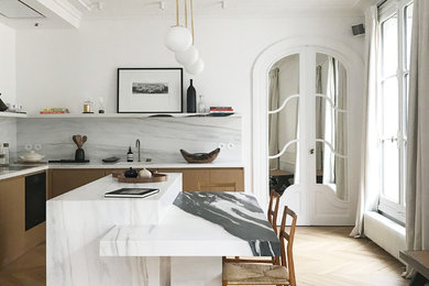 Exemple d'une cuisine tendance en L et bois clair avec une crédence blanche, une crédence en dalle de pierre, parquet clair, îlot, un sol beige et un plan de travail blanc.