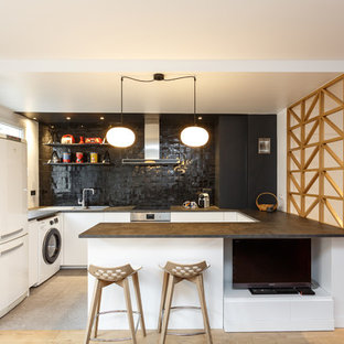 Exemple d'une cuisine ouverte scandinave en U de taille moyenne avec un placard à porte plane, des portes de placard blanches, un plan de travail en stratifié, une crédence noire, une crédence en carreau de terre cuite, un sol en carrelage de porcelaine, un sol gris, un évier posé, un électroménager blanc, une péninsule et un plan de travail noir.