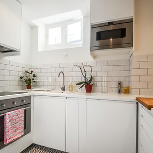 Aménagement d'une petit cuisine scandinave en U fermée avec un évier posé, un placard à porte plane, des portes de placard blanches, une crédence blanche, une crédence en carrelage métro, un électroménager en acier inoxydable et aucun îlot.