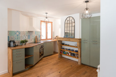 Scandi single-wall enclosed kitchen in Lyon with flat-panel cabinets, green cabinets, wood worktops, multi-coloured splashback, stainless steel appliances, medium hardwood flooring, no island and brown floors.