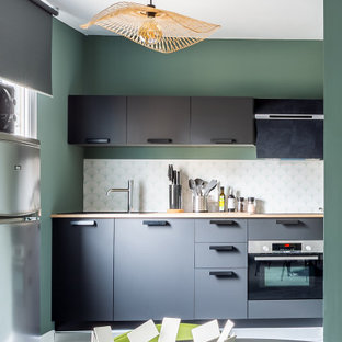 Inspiration pour une petit cuisine américaine linéaire design avec un évier encastré, un plan de travail en bois, un sol en vinyl, un sol gris, un placard à porte plane, des portes de placard noires, une crédence blanche, un électroménager en acier inoxydable, aucun îlot et un plan de travail beige.
