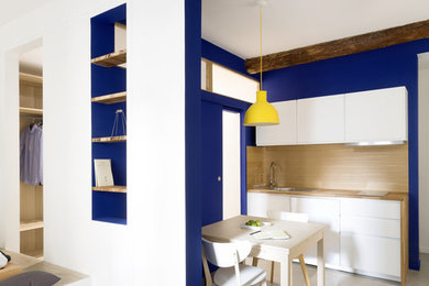 Idées déco pour une petite cuisine ouverte linéaire contemporaine avec un placard à porte affleurante, des portes de placard blanches et un plan de travail en bois.
