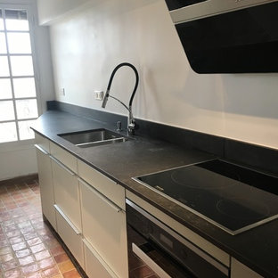 Inspiration for a small modern single-wall separate kitchen in Marseille with an integrated sink, granite benchtops, black splashback, panelled appliances and terra-cotta floors.