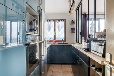 Modelo de cocina contemporánea pequeña con fregadero integrado, encimera de madera, puertas de armario azules, salpicadero multicolor, electrodomésticos de acero inoxidable y suelo de baldosas de cerámica