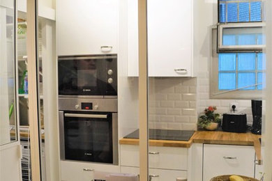 Aménagement d'une petite cuisine ouverte classique en L avec des portes de placard blanches, un plan de travail en bois, une crédence blanche, une crédence en carrelage métro et un sol en carrelage de céramique.