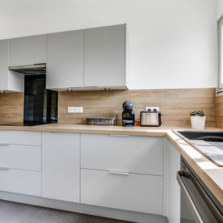 Large scandinavian l-shaped separate kitchen in Paris with a single-bowl sink, beaded inset cabinets, grey cabinets, laminate benchtops, beige splashback, black appliances, ceramic floors, no island, grey floor and beige benchtop.
