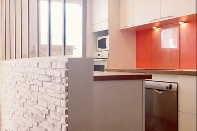 Zweizeilige, Mittelgroße Moderne Küche mit Unterbauwaschbecken, Kassettenfronten, weißen Schränken, Laminat-Arbeitsplatte, Küchenrückwand in Orange, Glasrückwand, Küchengeräten aus Edelstahl, Linoleum und buntem Boden in Paris