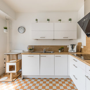 Idées déco pour une cuisine contemporaine en L avec un évier posé, un placard à porte plane, des portes de placard blanches, un plan de travail en bois, une crédence en bois, un électroménager noir, aucun îlot et un sol orange.