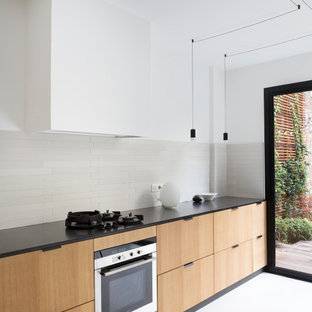 Design ideas for a large contemporary l-shaped eat-in kitchen in Paris with an undermount sink, flat-panel cabinets, beige cabinets, grey splashback, ceramic splashback, panelled appliances, concrete floors, no island, white floor and black benchtop.
