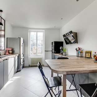 Large scandinavian eat-in kitchen in Paris with an undermount sink, beaded inset cabinets, grey cabinets, black appliances, ceramic floors, grey floor, beige benchtop, laminate benchtops and a peninsula.