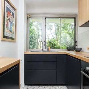 Diseño de cocina en L, nórdica, pequeña, cerrada, sin isla, con fregadero encastrado, armarios con paneles lisos, puertas de armario negras, encimera de madera, salpicadero de vidrio, suelo multicolor, salpicadero blanco, electrodomésticos de acero inoxidable, suelo de terrazo y encimeras marrones