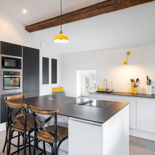 Réalisation d'une cuisine parallèle design de taille moyenne avec un évier 1 bac, un placard à porte plane, une crédence blanche, un électroménager encastrable, un îlot central, un sol gris, un plafond en bois et un plafond en poutres apparentes.
