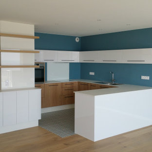 Mid-sized modern u-shaped open plan kitchen in Nantes with an integrated sink, beaded inset cabinets, white cabinets, glass sheet splashback, panelled appliances, cement tiles, with island, blue floor and blue benchtop.