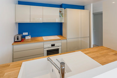 Cette photo montre une petite cuisine ouverte parallèle tendance avec un évier encastré, un placard à porte affleurante, des portes de placard beiges, un plan de travail en bois, une crédence bleue, un électroménager blanc, un sol en ardoise, un sol gris et un plan de travail beige.