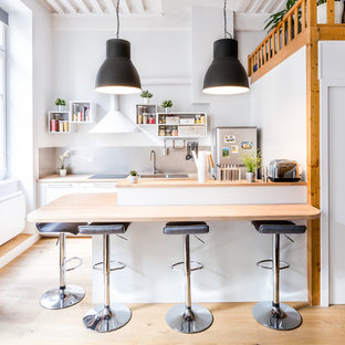 Inspiration pour une cuisine nordique avec un évier posé, un placard sans porte, des portes de placard blanches, un plan de travail en bois, une crédence grise, un électroménager en acier inoxydable, un sol en bois clair et une péninsule.