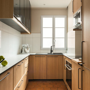 Idée de décoration pour une cuisine américaine tradition avec un évier posé, un placard à porte plane, des portes de placard en bois brun, une crédence blanche, un électroménager encastrable, un sol en carreau de terre cuite, aucun îlot, un sol rouge et un plan de travail blanc.