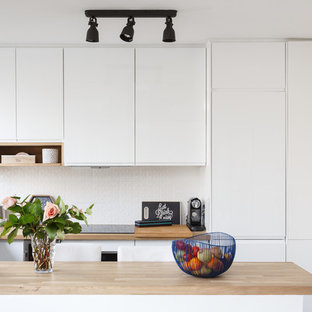 Modelo de cocina en U, minimalista, pequeña, abierta, con armarios con paneles lisos, puertas de armario blancas, encimera de madera, salpicadero blanco, salpicadero de azulejos de cerámica, electrodomésticos de acero inoxidable, suelo de azulejos de cemento, suelo azul, encimeras beige, fregadero bajoencimera y península