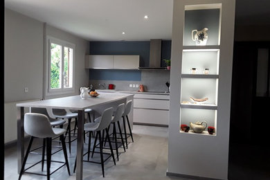 Mittelgroße Moderne Wohnküche in L-Form mit flächenbündigen Schrankfronten, Kücheninsel und grauem Boden in Lyon